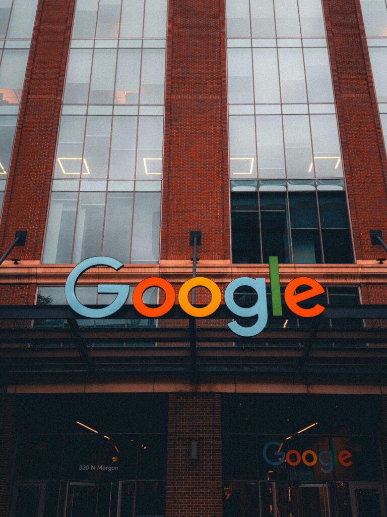 Exterior view of a brick-building storefront with a large colorful Google logo above the entrance, signifying Google offices