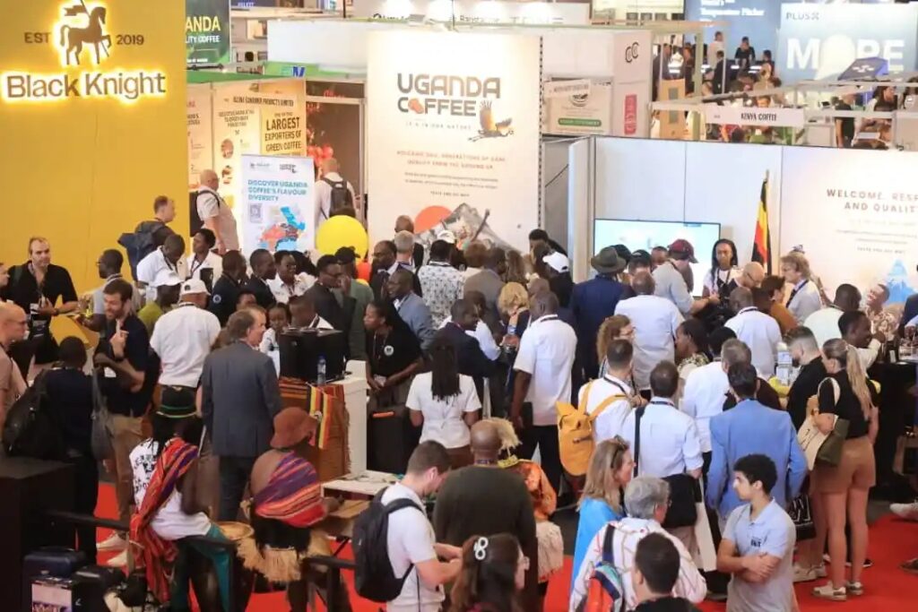 Crowded exhibition hall with multiple coffee booth displays, including Uganda Coffee and Black Knight signage.