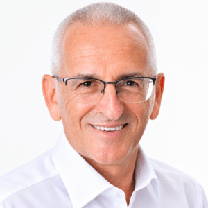 15 July - Executive Appointments – African Marketing Confederation – African Marketing Confederation Portrait of a smiling older man with gray hair and rectangular glasses wearing a white shirt, facing the camera.