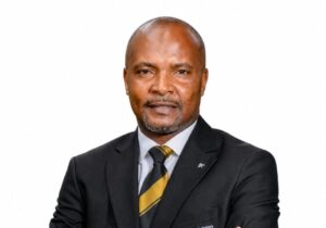 23 July - AMC Member News – African Marketing Confederation – African Marketing Confederation Portrait of a middle-aged man in a black suit and gold-and-black striped tie, looking at the camera against a white background.