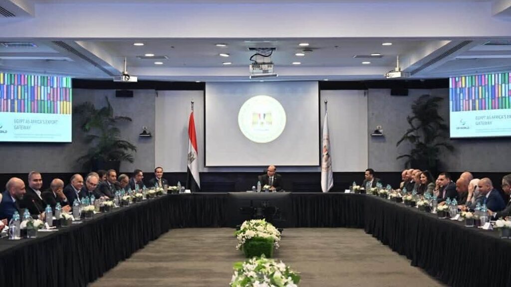 Formal international meeting in a large conference room with a U-shaped table and delegates seated on both sides, a speaker at center podium.