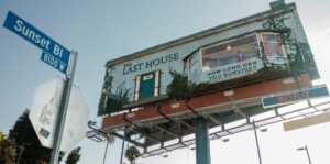 A large billboard atop a highway overpass advertising 'The Last House' with a 'How long can you survive?' window display and a Netflix sign below.