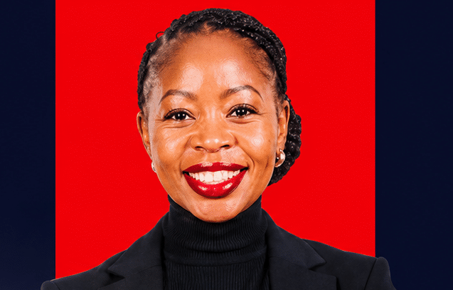 Portrait of a smiling woman with braided hair wearing a black turtleneck and blazer against a red backdrop.