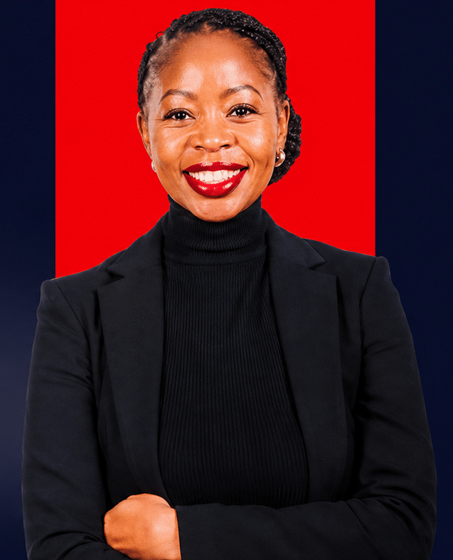 Smiling woman in a black blazer and turtleneck, standing against a red panel backdrop.