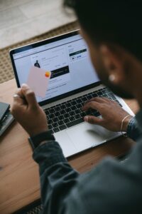 Two people shopping online on a laptop one holding a credit card ready to pay at checkout