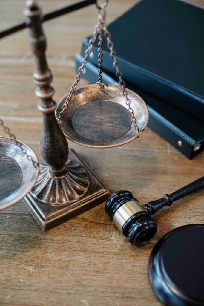 Close-up of a brass balance scale and gavel with a legal book in the background, symbolizing justice and law.