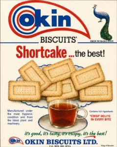Okin biscuits advertisement showing a plate of rectangular shortbread biscuits and a cup of tea with a peacock logo on the top right and the caption 'shortcake the best '