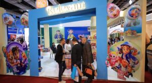 4 August - Business Strategy – African Marketing Confederation – African Marketing Confederation Blue exhibition booth labeled 'Relevant' at a trade show, with people talking near product shelves and balloons in the background.
