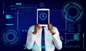 Person in a business shirt and tie holds a tablet up, obscuring their face, with glowing blue futuristic data HUD graphics around it.