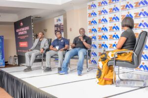 September Amc Member News Panel of four men seated on a stage during a conference with a large screen reading 'sales & customer service conference ' and a backdrop covered in 'zambia institute of marketing' logos