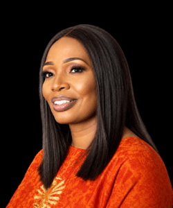 Portrait of a smiling woman with long straight black hair and an orange textured top against a black background