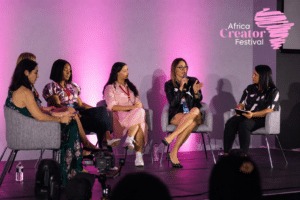 September Creator Economy Panel of five women seated on stage at africa creator festival speaking into mics under pink lighting logo visible in top right