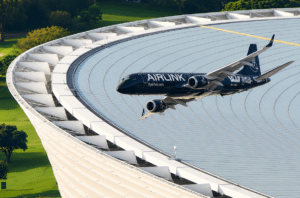 September Brand Activations Dark blue airlink jet flying above a large circular domed roof with white support structures and surrounding greenery