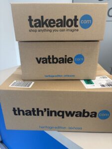 Stacked cardboard shipping boxes with takealot vatbaie and thatinqwaba branding and blue circular logos