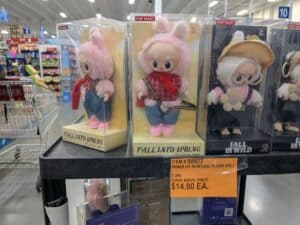 Row of boxed plush bunny dolls on a store shelf with pink fur and colorful outfits