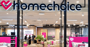 October Executive Appointments Homechoice storefront with bright logo and pink branding showing a showroom full of sofas pillows and bedding inside