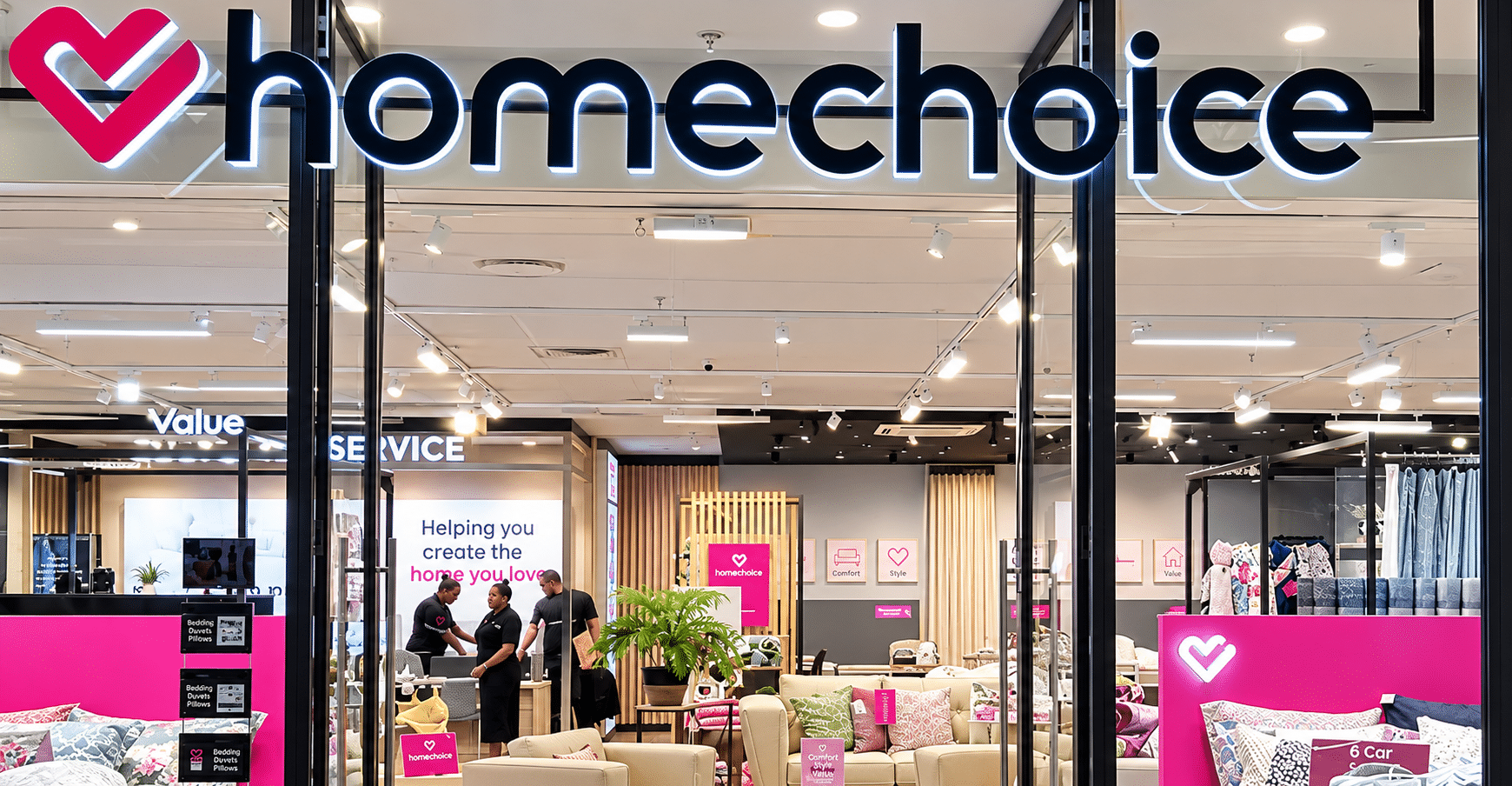 October Executive Appointments Homechoice storefront with bright logo and pink branding showing a showroom full of sofas pillows and bedding inside